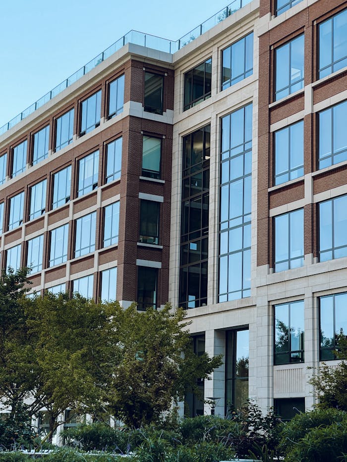 Contemporary office building exterior featuring large glass windows and green surroundings.